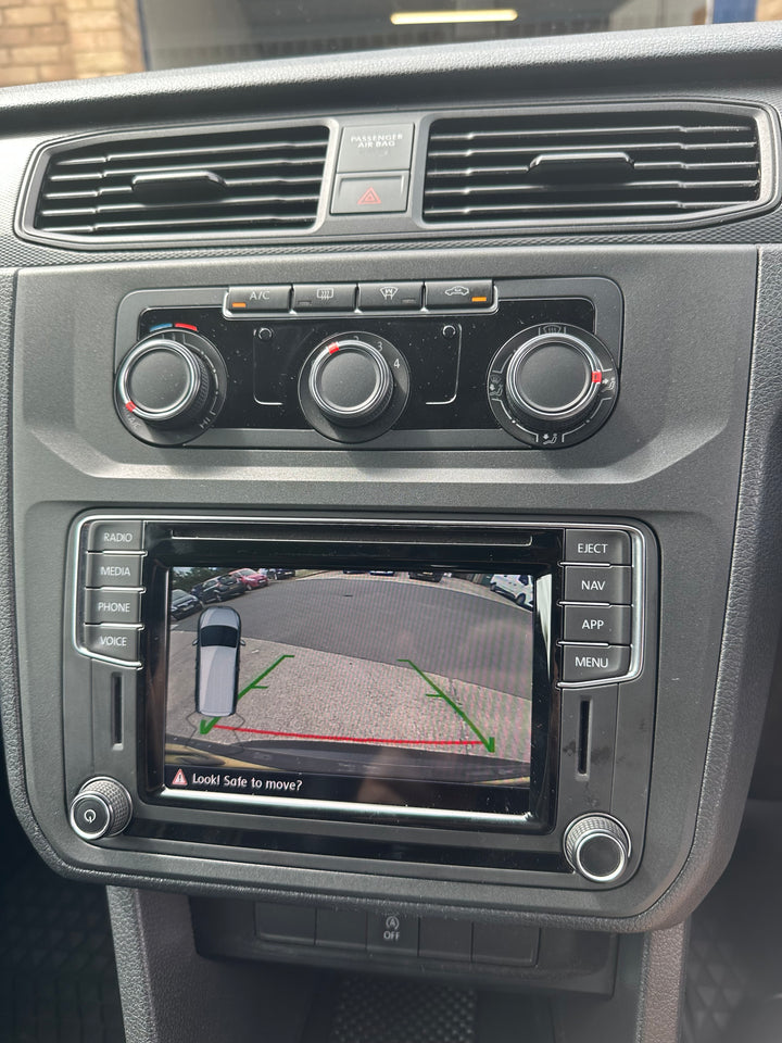 Touchscreen radio showing a reversing camera view with guide lines, set below climate control knobs and air vents