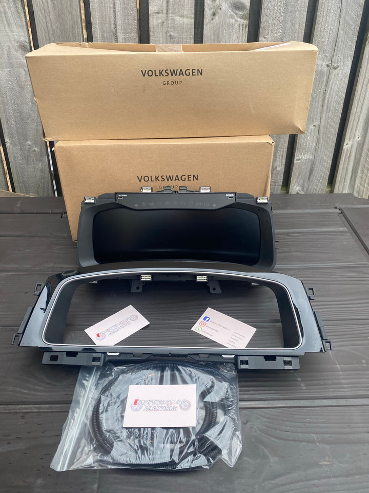 Blank digital instrument cluster with black bezel and a bagged wiring loop in front of two cardboard boxes