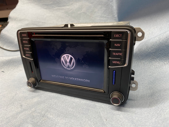 Head unit at an angle on a blue blanket showing the VW logo and ‘Welcome to Volkswagen’, with CD slot and push buttons