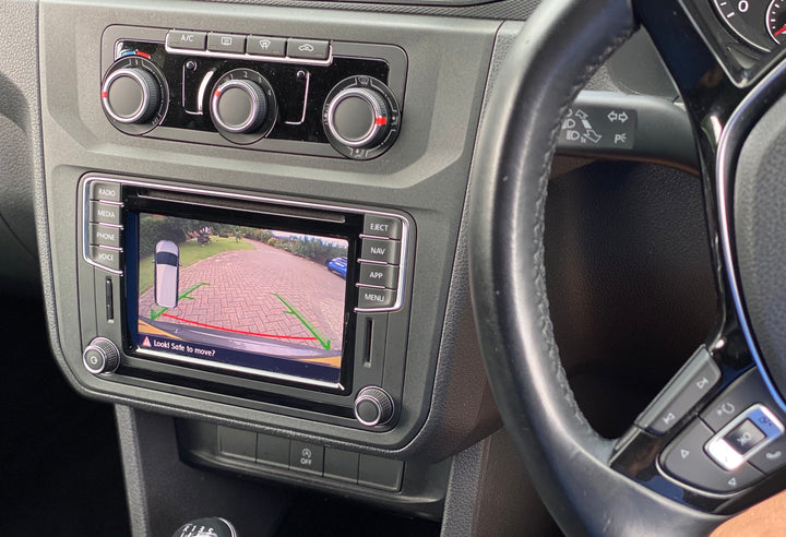 Dashboard with climate dials and a touchscreen showing a rear camera view of block paving with red and green guide lines