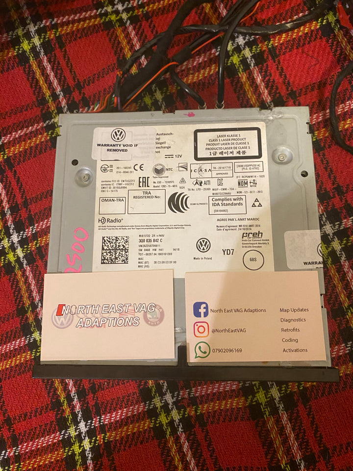 Label on a head unit reading MIB STD2 ZR +/NAV and 3Q0 035 842 C, with two North East VAG cards on red tartan cloth